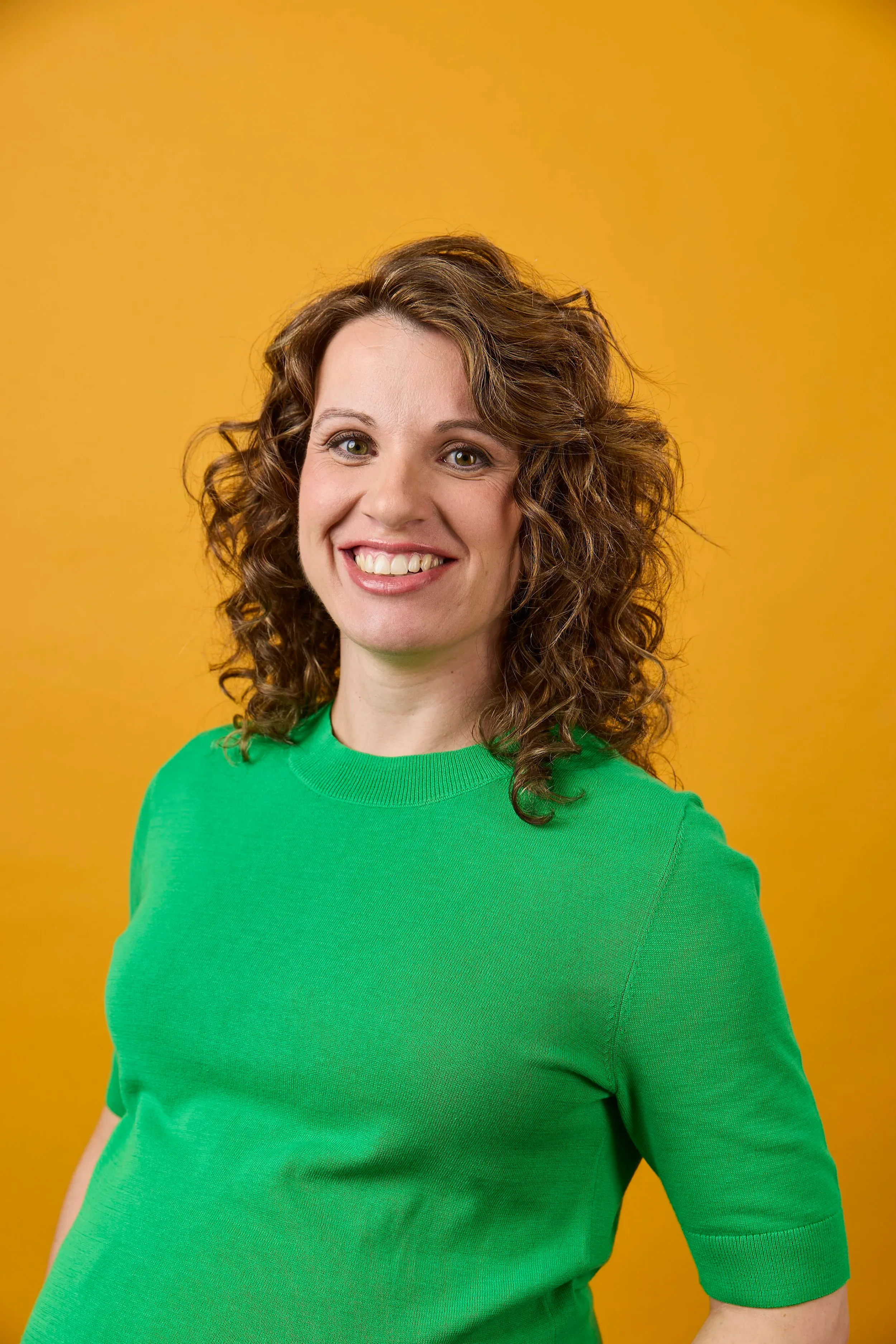 Dr Veli Kiriakova, endocrinologist, smiling in a green top against a yellow background