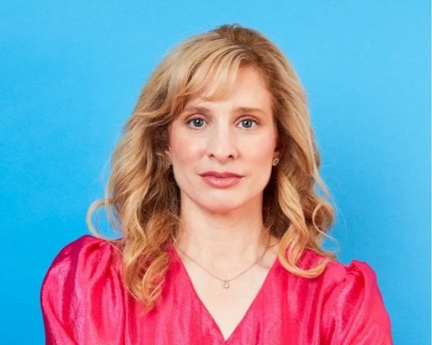 Dr Raelia Lew, fertility specialist at Women's Health Melbourne, smiling in a pink blouse against a blue background