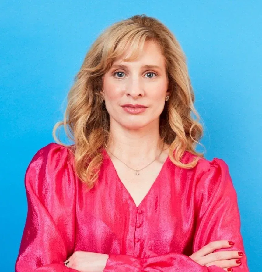 Dr Raelia Lew, fertility specialist at Women's Health Melbourne, smiling in a pink blouse against a blue background