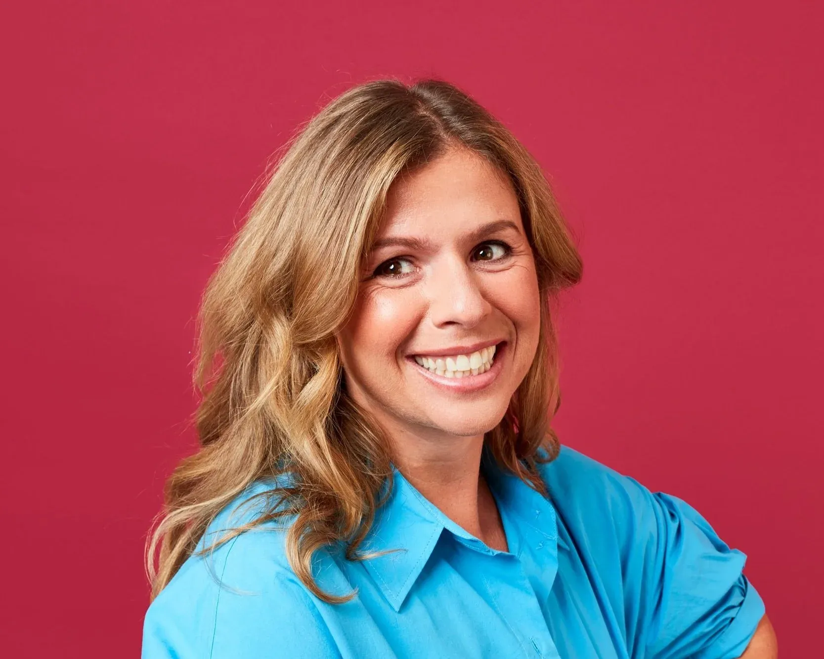 Georgia, naturopath, smiling in a blue shirt against a red background