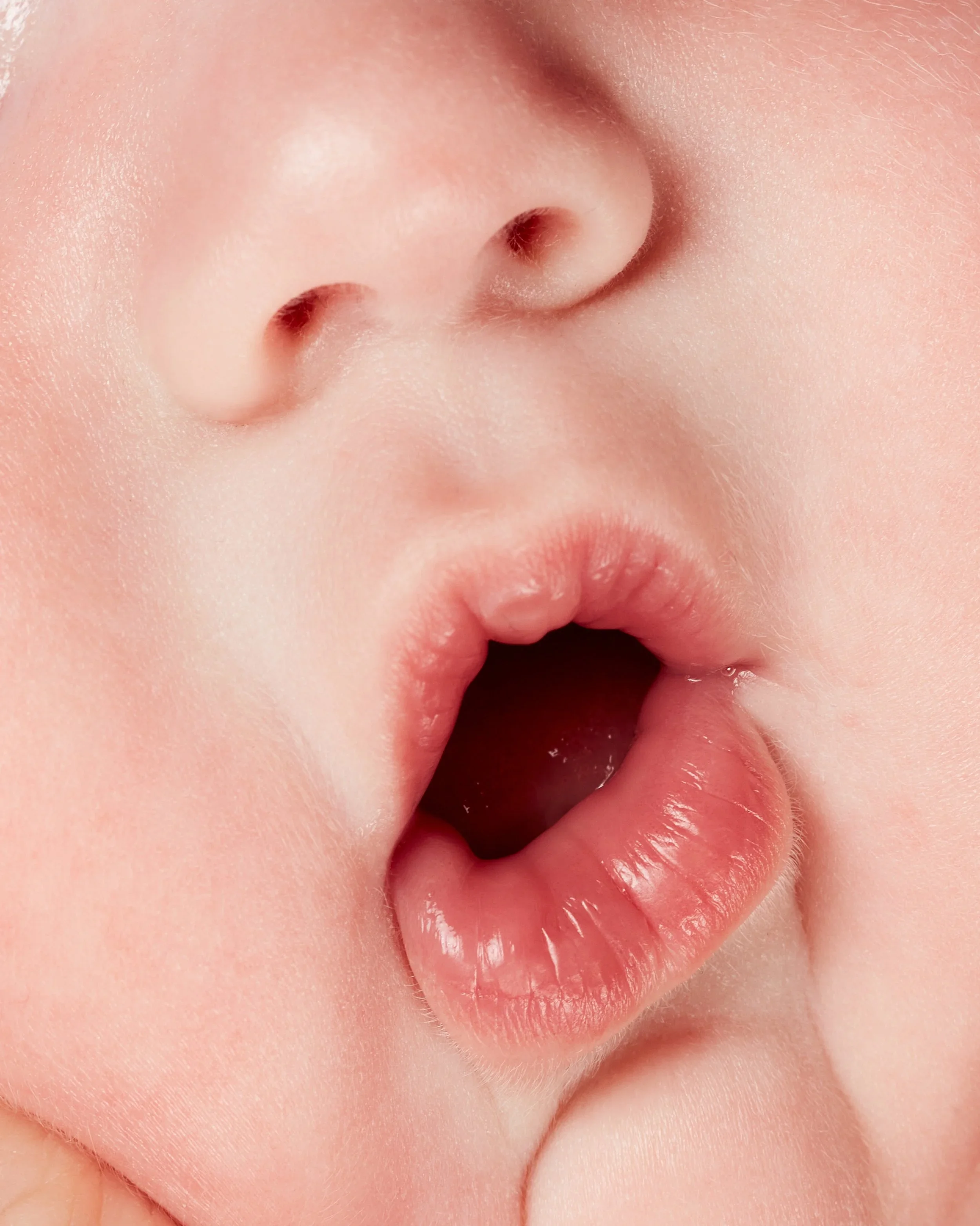 Close-up of a newborn baby's face with lips pursed