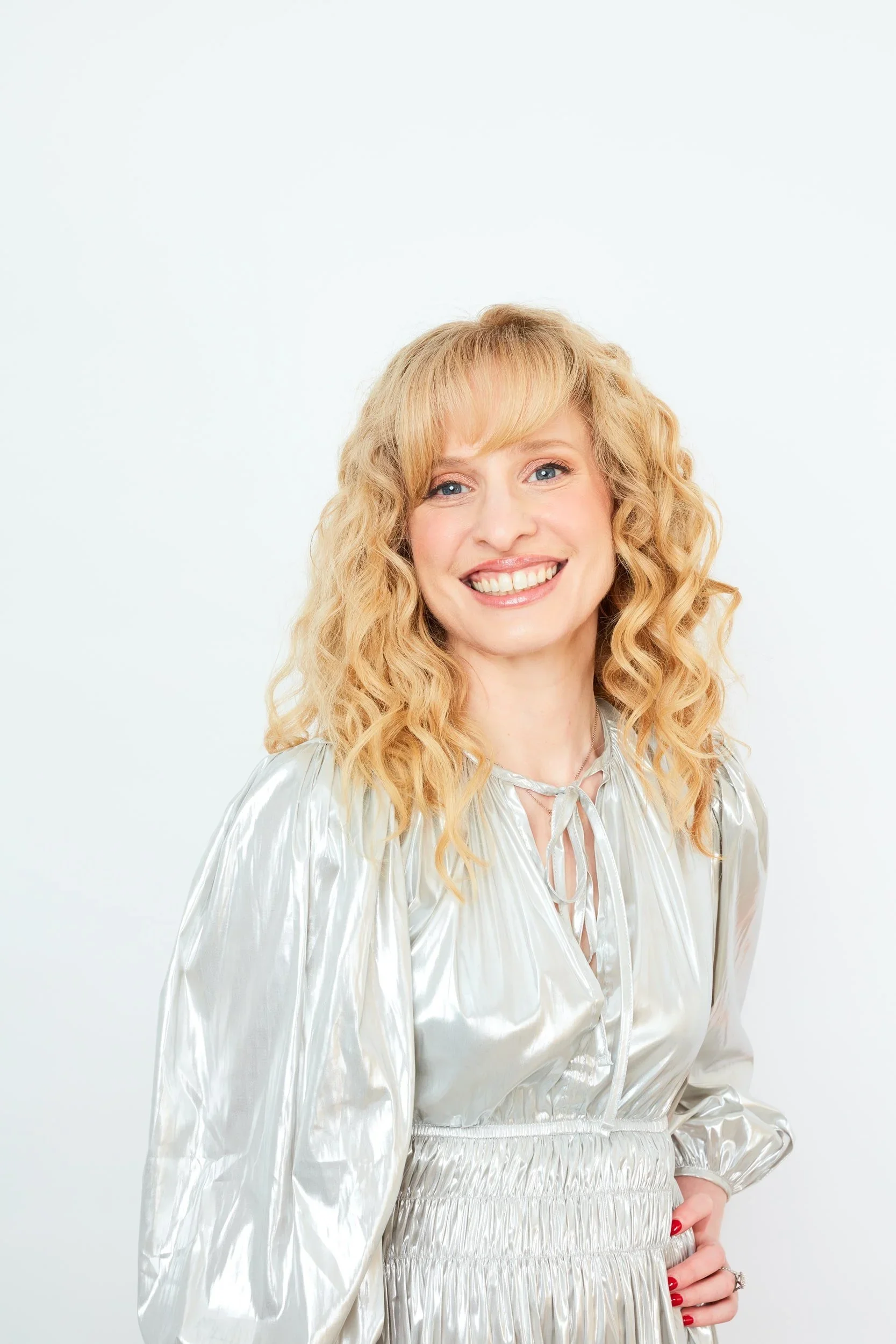 Dr Raelia Lew smiling in a metallic silver dress against a white backdrop