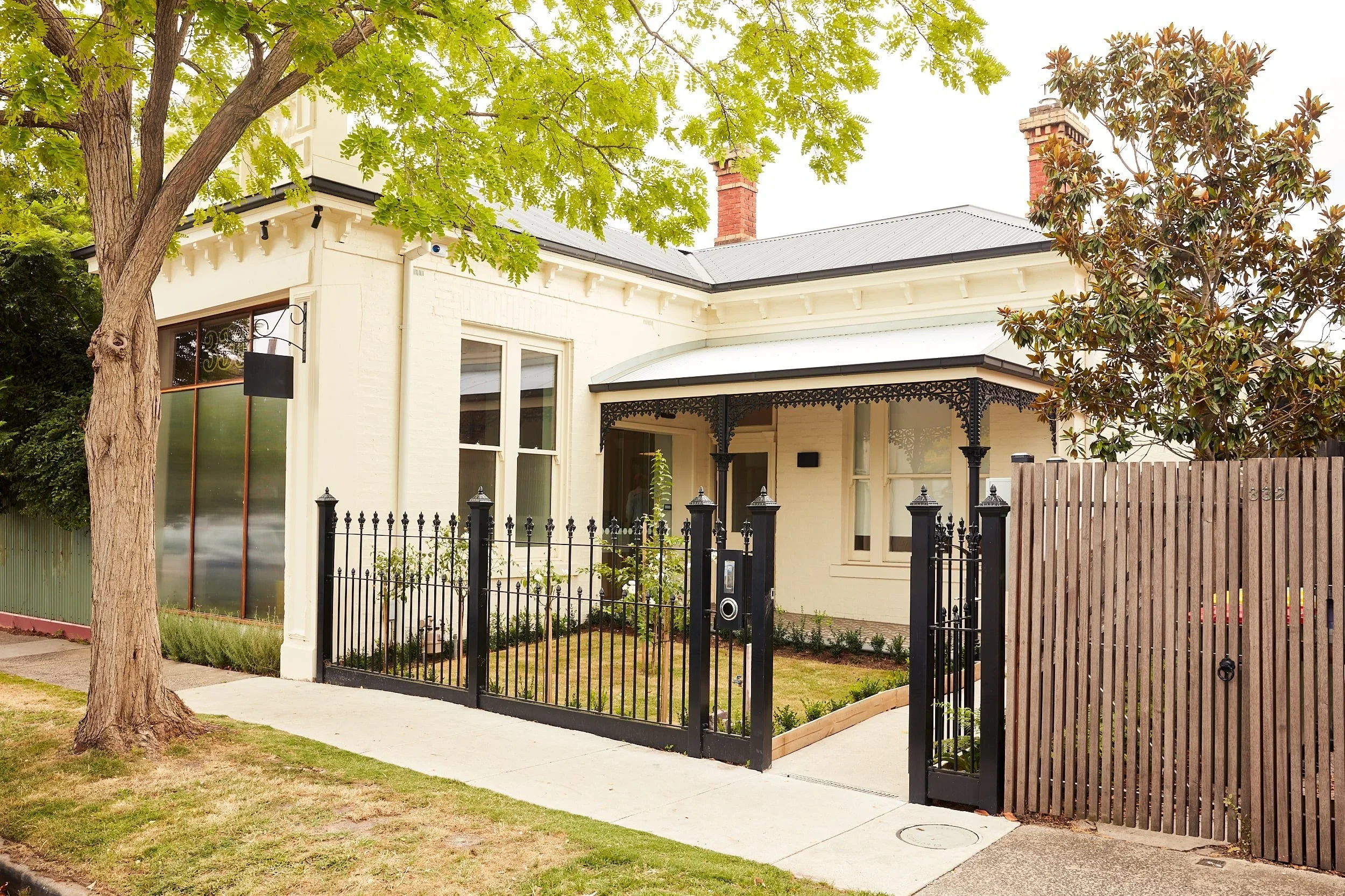 Women's Health Melbourne clinic, a cream Victorian house with a black iron fence and street tree